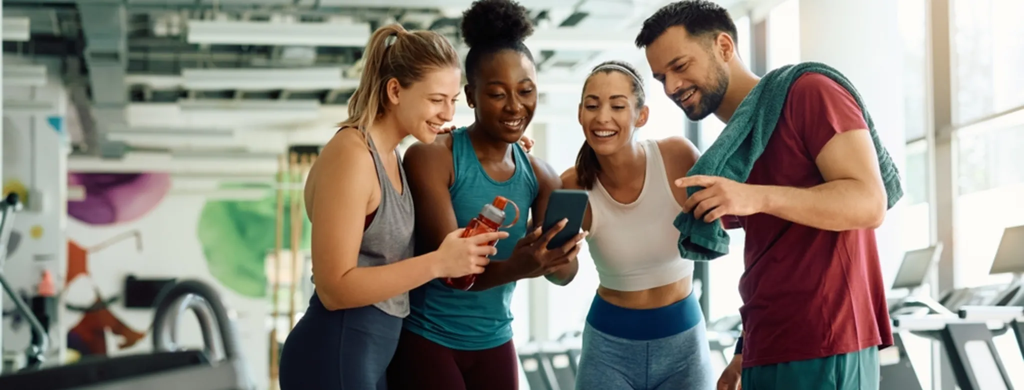 4 people looking at a phone at a gym
